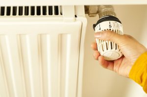 Kéz a radiátor termosztátján – radiátor és fűtőtest festése