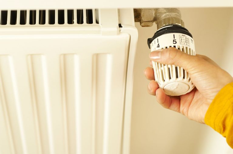 Kéz a radiátor termosztátján – radiátor és fűtőtest festése